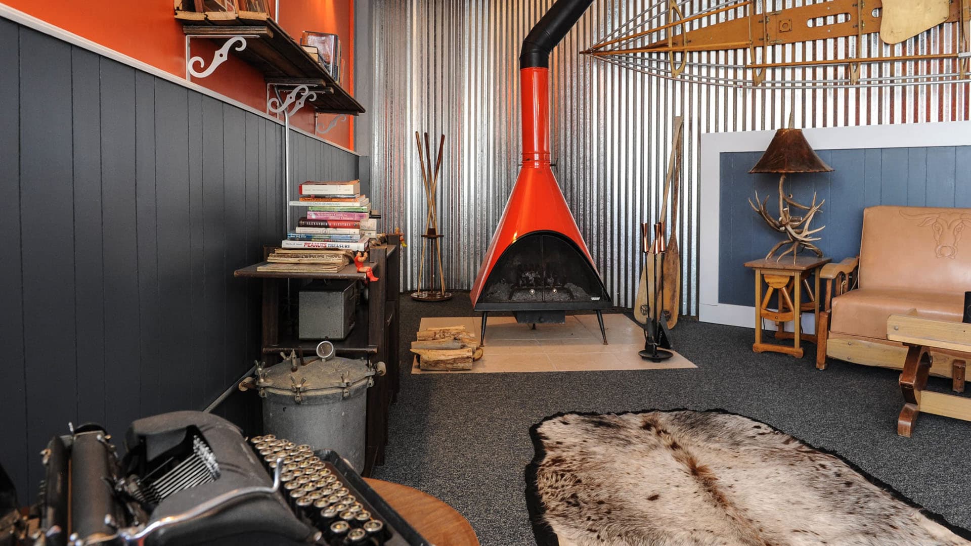A cozy interior featuring a vibrant orange fireplace, vintage typewriter, and rustic decor.